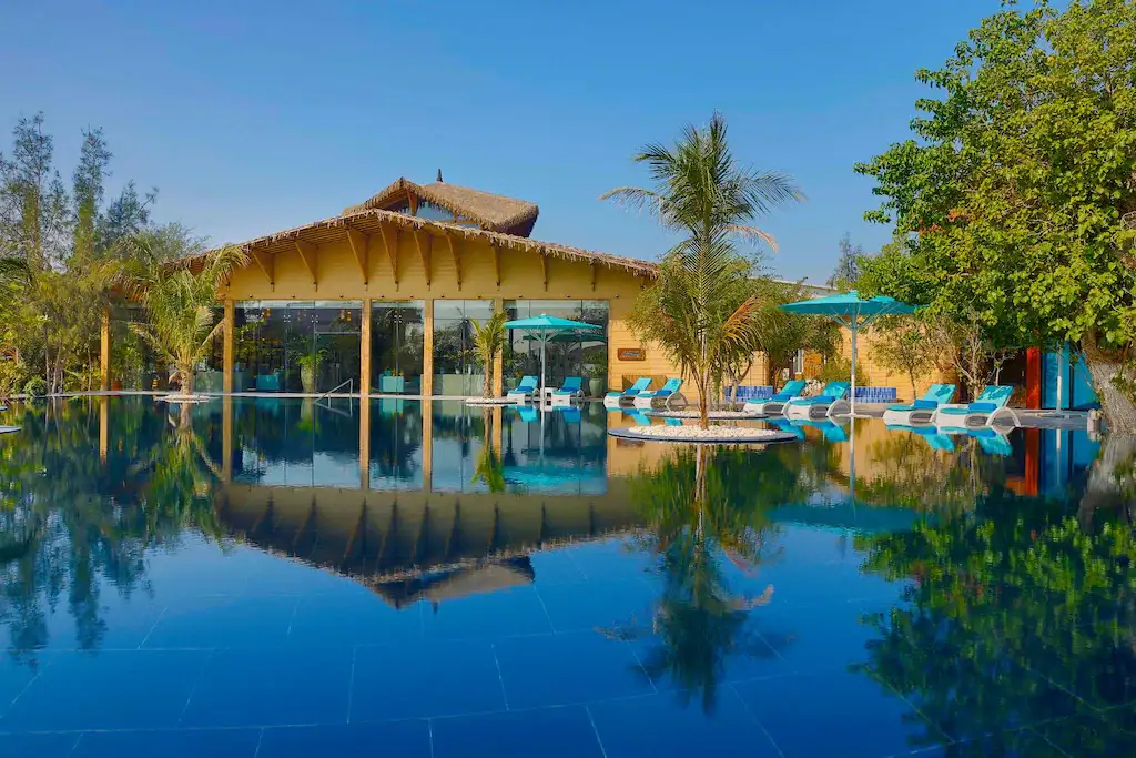 Palm-lined infinity pool and island resort pavilion
